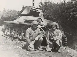 Photo of a small tank with two soldiers in front of it