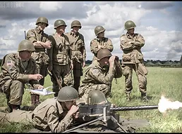 Soldiers with a machine gun firing and other stood behind them watching
